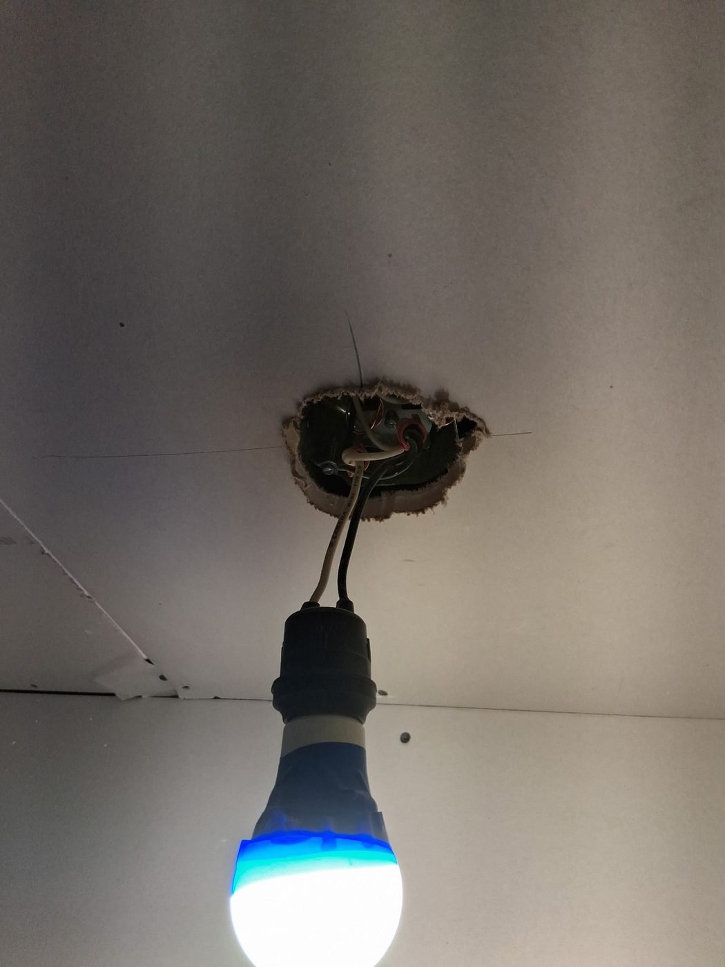 A temporary light bulb hanging from a ceiling electrical box