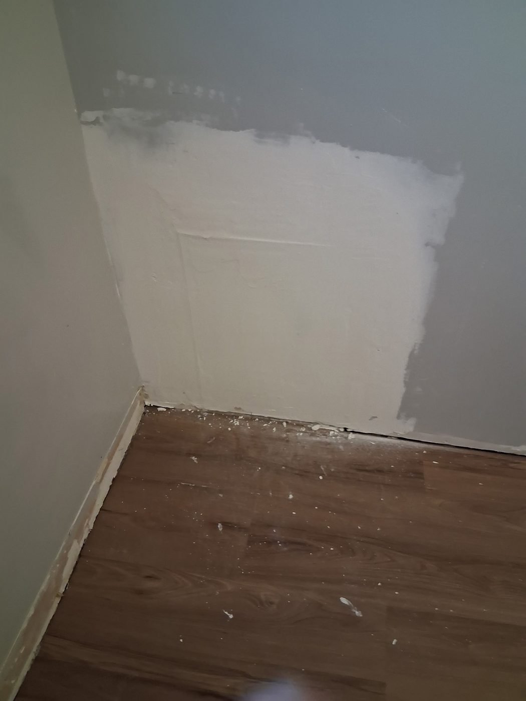A large replaced and taped section of drywall in the corner of a room