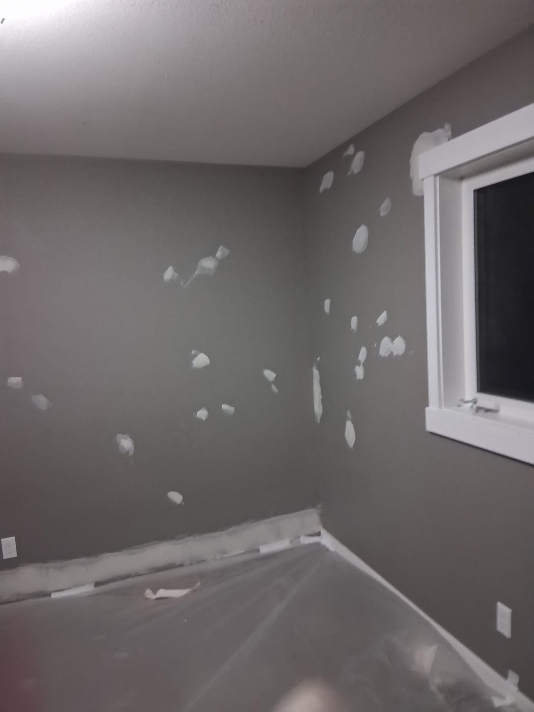 Bedroom wall covered in white filler patches before sanding