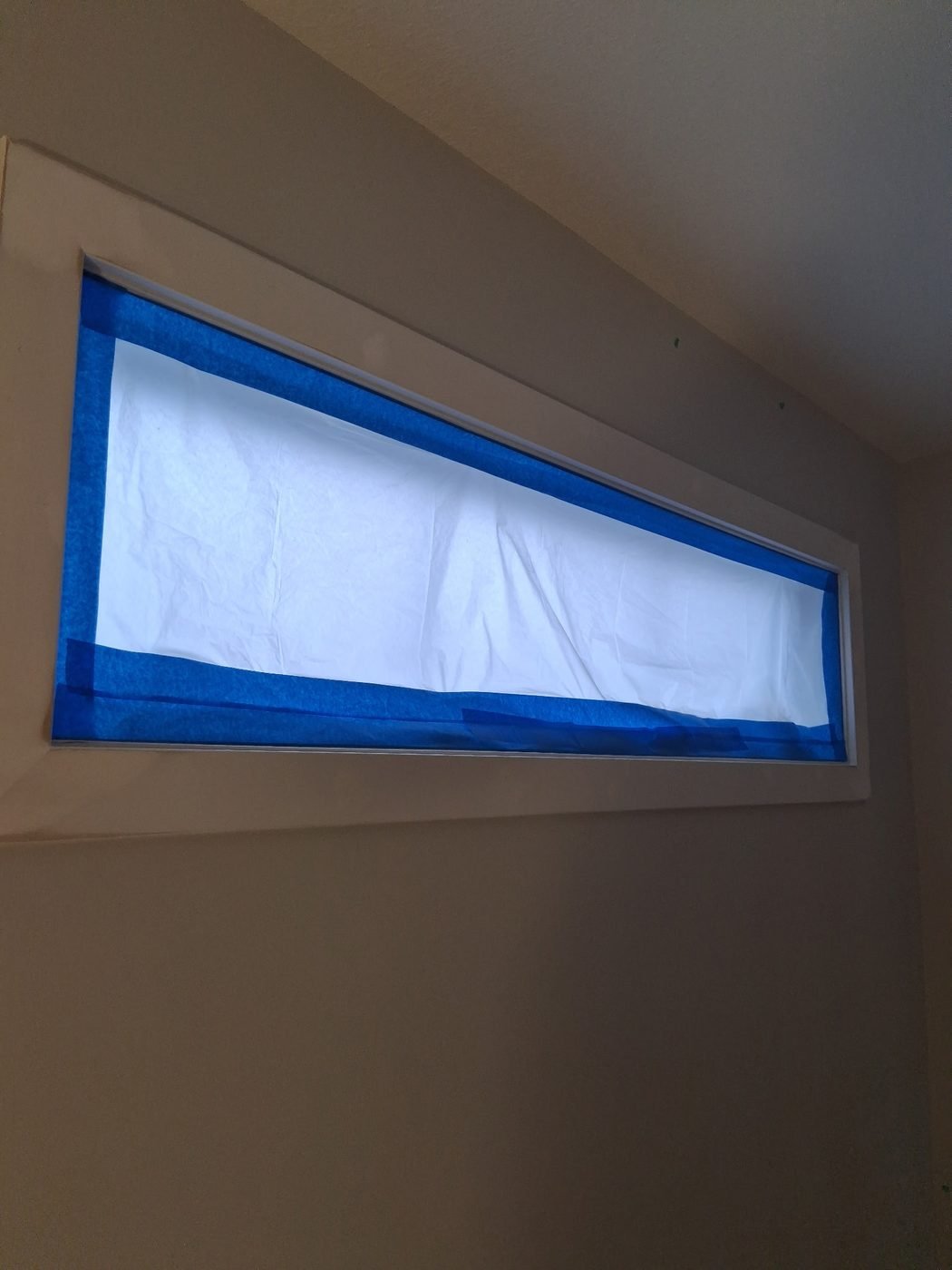 A long transom window fully masked with paper and blue tape