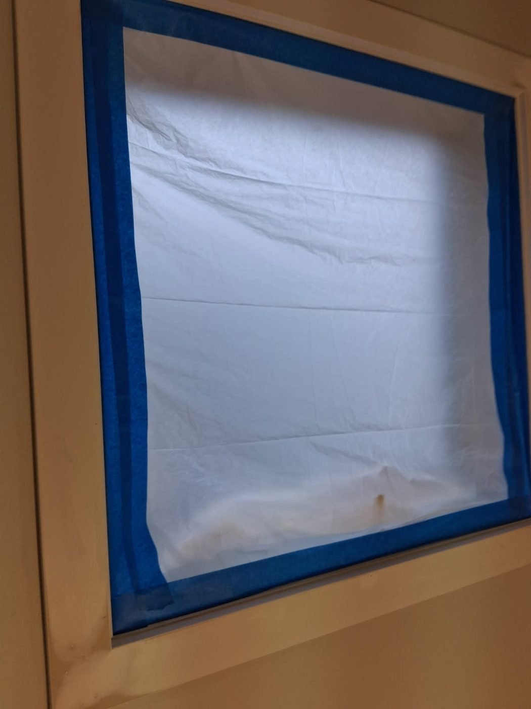 A window masked with paper and blue painters tape