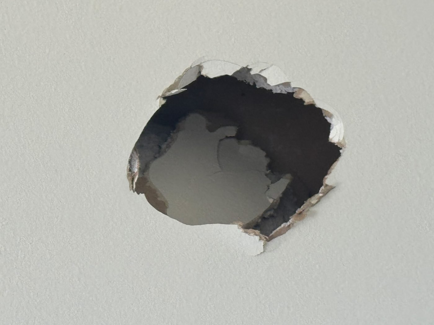 A hole punched through a textured drywall wall