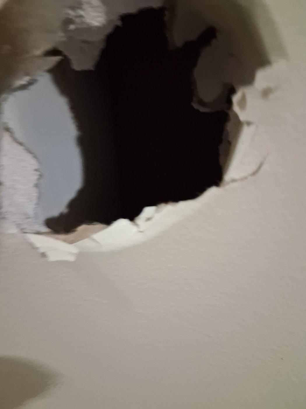 A hole in a wall opening through to the stud cavity